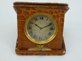 An early 20th century folding 8 day travel clock in mock croc leather case.Goldsmiths & Silversmiths