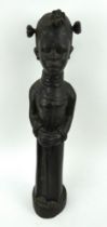 A large carved ebony wood African figure of a standing female in long robes. Height 56cm