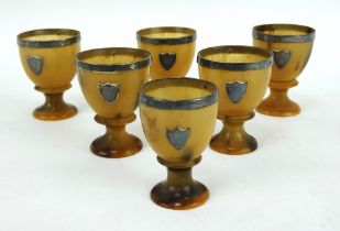Set of six silver mounted turned horn eggcups, each with silver rim and blank shield.