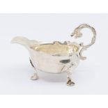 A George II silver sauceboat, with three shell shaped feet, single handle with mythical serpent