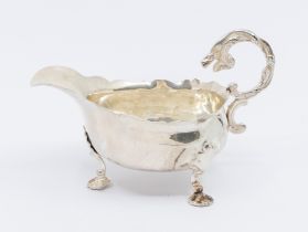 A George II silver sauceboat, with three shell shaped feet, single handle with mythical serpent