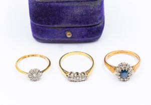 Three stone set 18ct gold rings, to include an Edwardian diamond set flower cluster ring, size M,