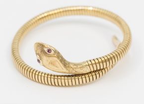 A 9ct gold serpent bangle, comprising a coiled form, the head with small ruby set eyes and