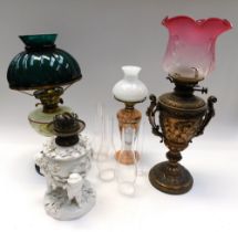 A collection of four 20th century oil lamps to include; an elaborate ceramic oil lamp, with stylised