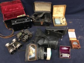 Collection of vintage cameras in cases. Early 20th century racing binoculars, gas masks and razors