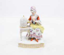 Meissen - A 20th century porcelain figure of a Lady seated on a chair, with birdcage on side