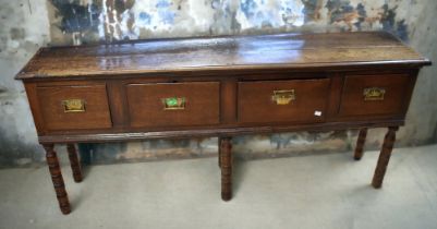 A George III solid English oak slender four drawer dresser base with brass swing handle and turned