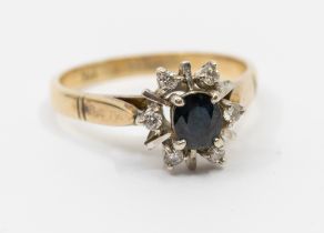 A sapphire and diamond 9ct gold ring, comprising an oval claw set sapphire set to the centre with