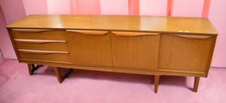 A 1980s teak-effect sideboard of two central cupboards, one pull down door and three drawers, 205