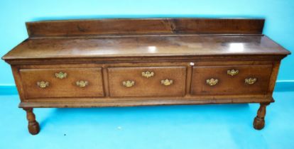 An early George III solid English oak dresser base with three deep front drawers and three brass