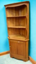 A late 20th century Ercol pine corner unit with two display shelves and cupboard to base.