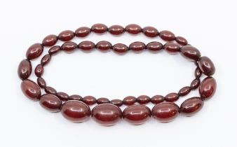 A graduated cherry coloured bead necklace, comprising a single row of graduated oval beads, the