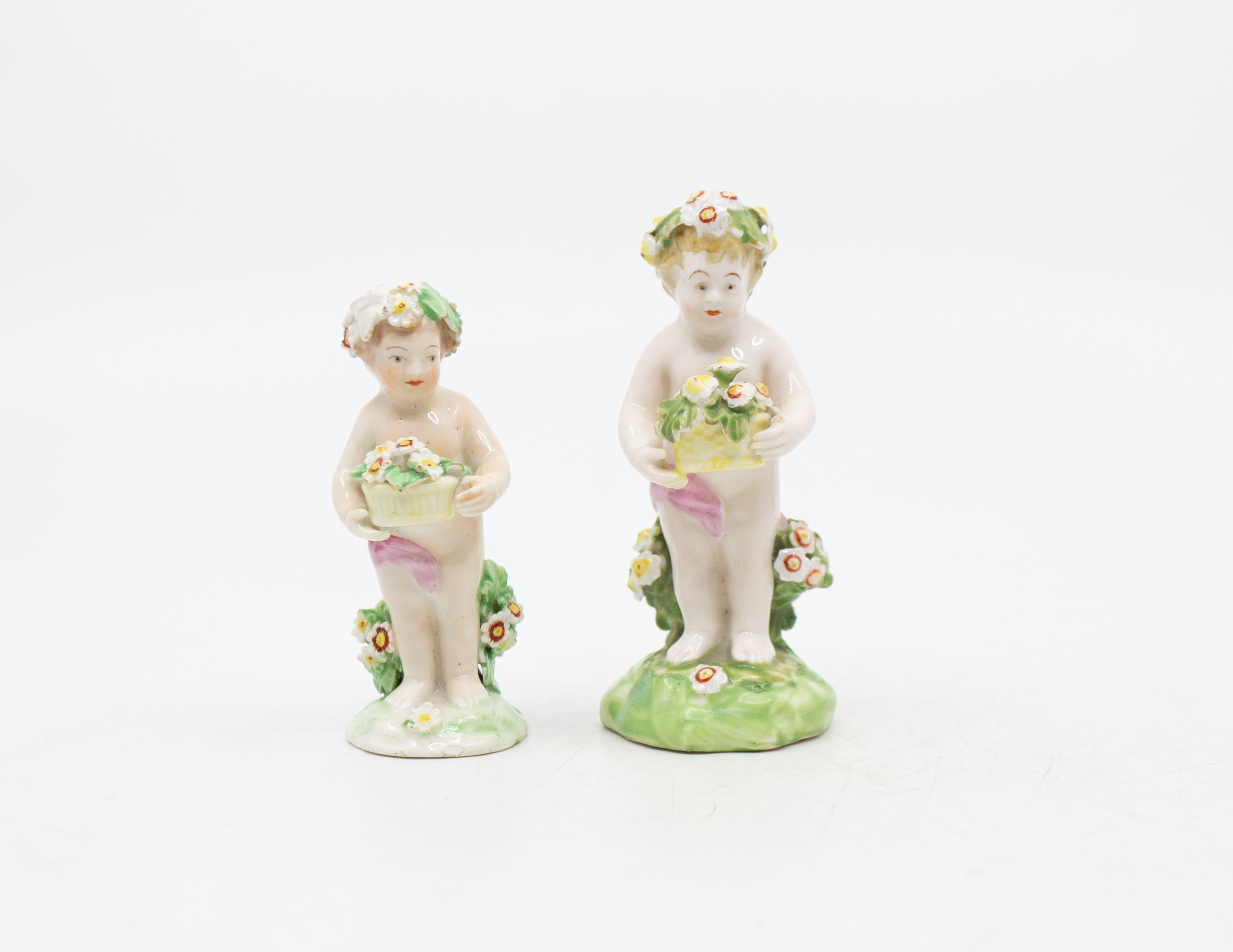 Two late 18th century porcelain putti holding bouquets of flowers, with patch marks to base. Good