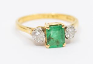 An emerald and diamond 18ct gold ring, comprising an emerald cut emerald claw set to the centre with