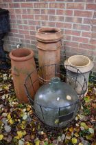 A large carboy and cage along with 3 chimney pots.