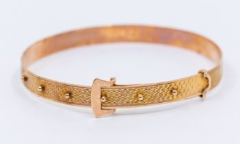 An early 20th century 9ct rose gold bangle in the form of a buckle, comprising machine engraved