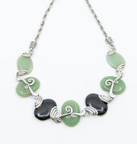 A jadeite and metal necklace, comprising five oval cabochon jadeites to the front, with two oval