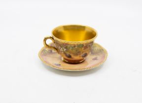 James Skerett for Royal Worcester - A hand painted cup and saucer, with elaborate gilding, signed