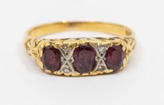A ruby and diamond 18ct gold three stone ring, comprising three oval rubies, diamond accents to a