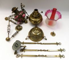 A late 19th century ruby glass hanging oil lamp, with elaborate brass casing and detail, in the