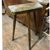 An Elm and pine rustic vernacular joined stool, trapezium shaped seat, raised on three splay legs.