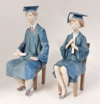 A unusual pair of LLadro male and female graduates sat on chairs with gowns and hats and scrolls