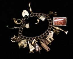 A 9ct gold charm bracelet with padlock clasp. Featuring 20 charms, some hallmarked, some in unmarked