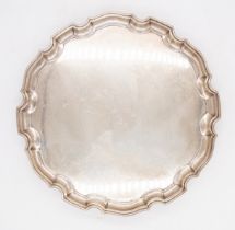 A Georgian style silver pie crust salver on three scroll feet, hallmarked by Adie Brothers,