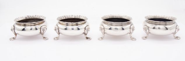 A set of four Georgian style silver circular salts, gadroon borders on three lion's head and paw