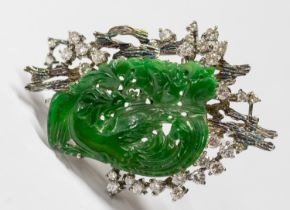 A diamond and jadeite white metal pendant/brooch, comprising a carved bird, with a bark like