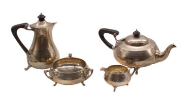An Arts & Crafts four piece silver tea service comprising teapot, hot water jug, tri-handled sugar