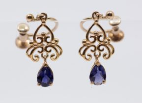 A pair of iolite and gold drop earrings, comprising a pear cut iolite drop, to a scrolled wire