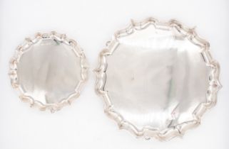 A pair of Edwardian graduating silver salvers with cut card borders, plain reserves on three hoof