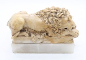 A 19th century alabaster figure of a Lion laying down and head on paws, on a rectangular base upon a
