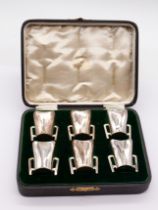 A set of six Edwardian silver tots in the form of plain miniature four handled tygs, hallmarked by