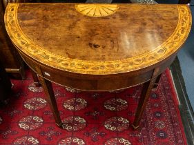 A George III inlaid mahogany fold over demi-lune card table, inlaid paterae to central top with band