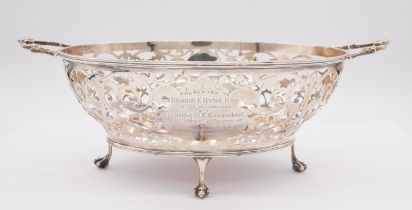 An Edwardian silver reticulated two handled bowl on four ball and claw feet, the central cartouche