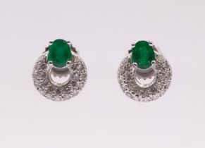 A pair of emerald and diamond 18ct white gold earrings, each comprising a single oval claw set