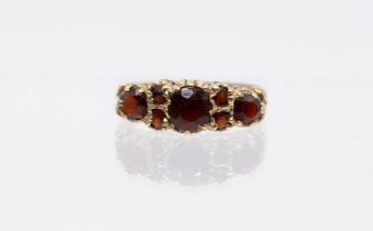 A garnet and 9ct gold ring, comprising three graduated round mixed cut garnets with smaller garnet