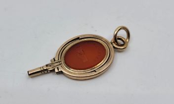 A yellow metal and carnelian seal and pocket watch key swivel fob, the oval seal/key grip set