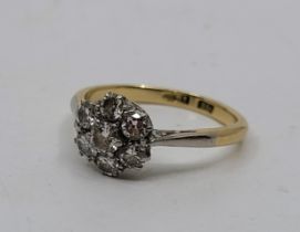 An 18ct. gold and diamond cluster ring, set single round brilliant cut diamond to raised centre
