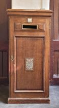 A very large Edwardian oak hall post box, having rectangular moulded top above panelled door