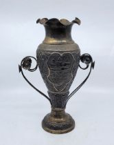 An Indian white metal twin handled baluster form vase, having undulating rim, the side repousse