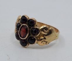 A Georgian precious yellow metal and garnet ring, the flower form centre with eight full rose-cut