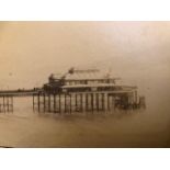 Photograph mounted on card of a seaside resort, pier and beach.