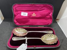 Hallmarked Silver: Pair of cased serving spoons with scroll pattern bowls and shell handles