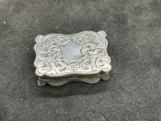 Early 19th cent. White metal vinaigrette, shaped edge, engraved decoration to the front and back,
