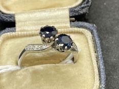 Jewellery: White metal crossover ring consisting of two circular cut sapphires, estimated weight