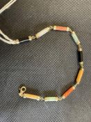 Jewellery: Yellow metal bracelet consisting of cylindrical links of different coloured jade.