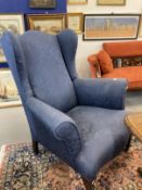 20th cent. Blue upholstered wingback armchair on square tapering front legs supported on brass